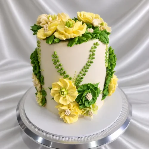 Lemon Blossom Floral Cake with yellow and white hand-piped buttercream flowers and green foliage